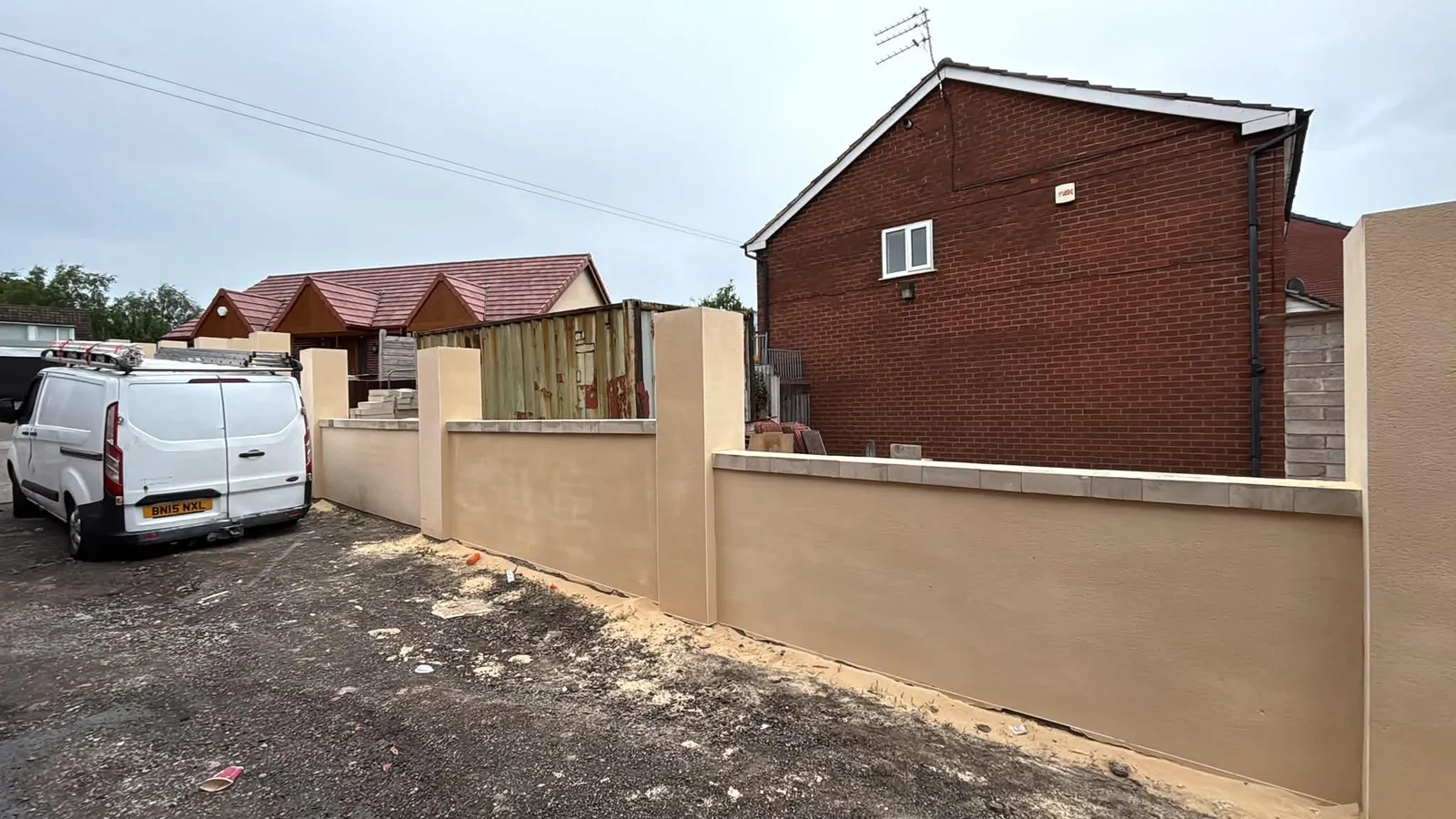 Completed cream render on garden walls and pillars beside a brick house