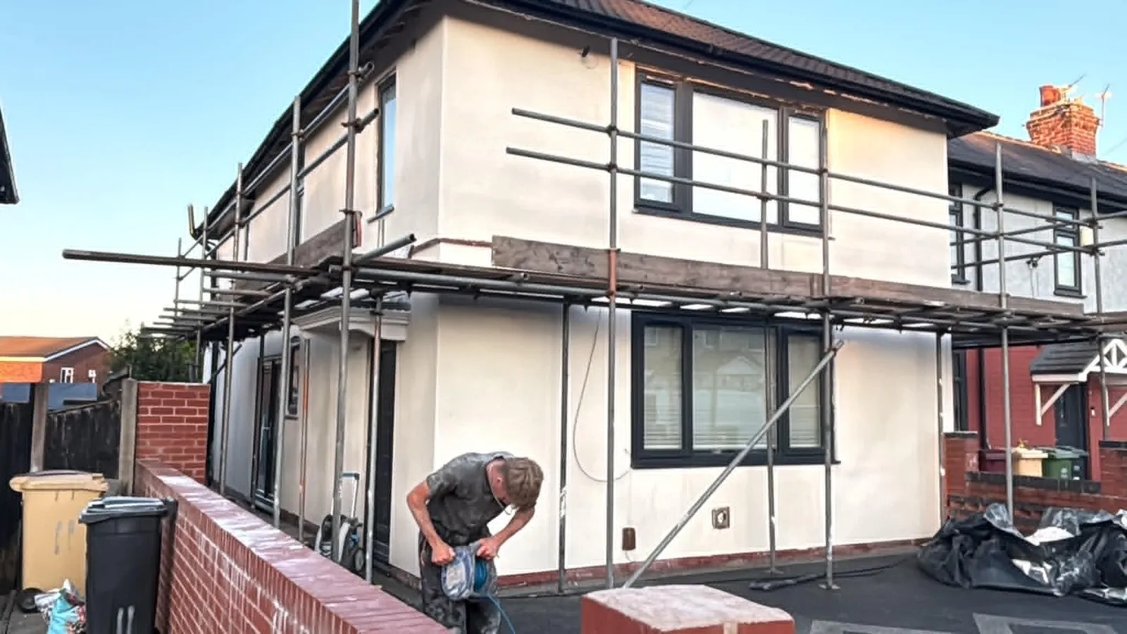 Fresh render wrapping the corner of a detached house, scaffold still in place