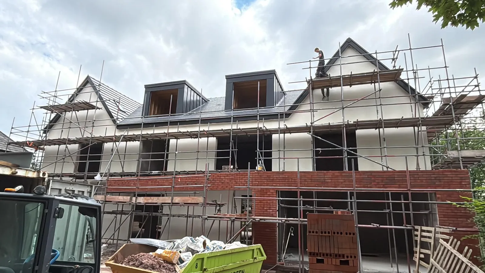 Render base coat applied to a large detached house with dormers, scaffolding still up