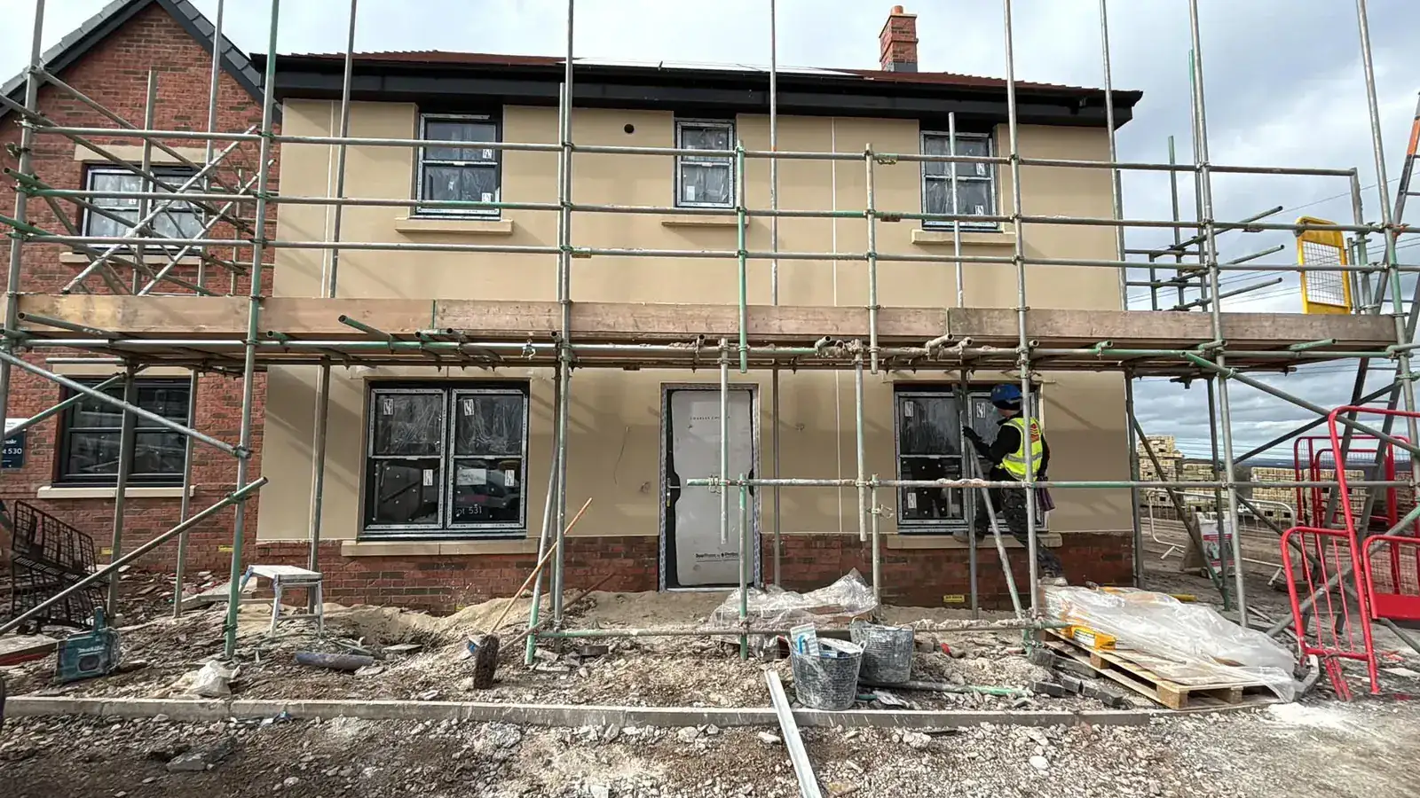 New-build houses finished in sand-coloured monocouche render on a development site