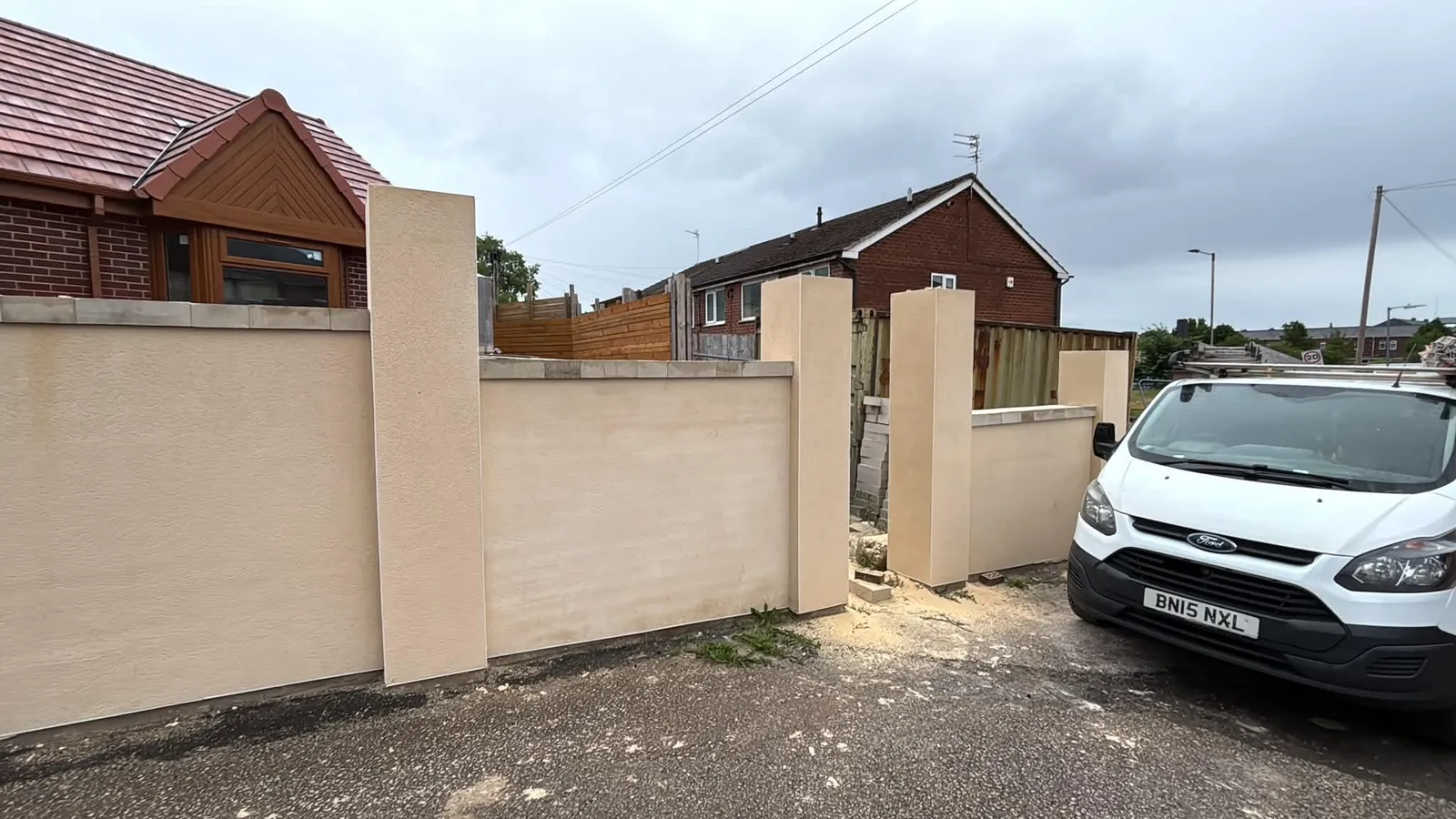 Rendered boundary wall and pillars finished in cream with stone copings